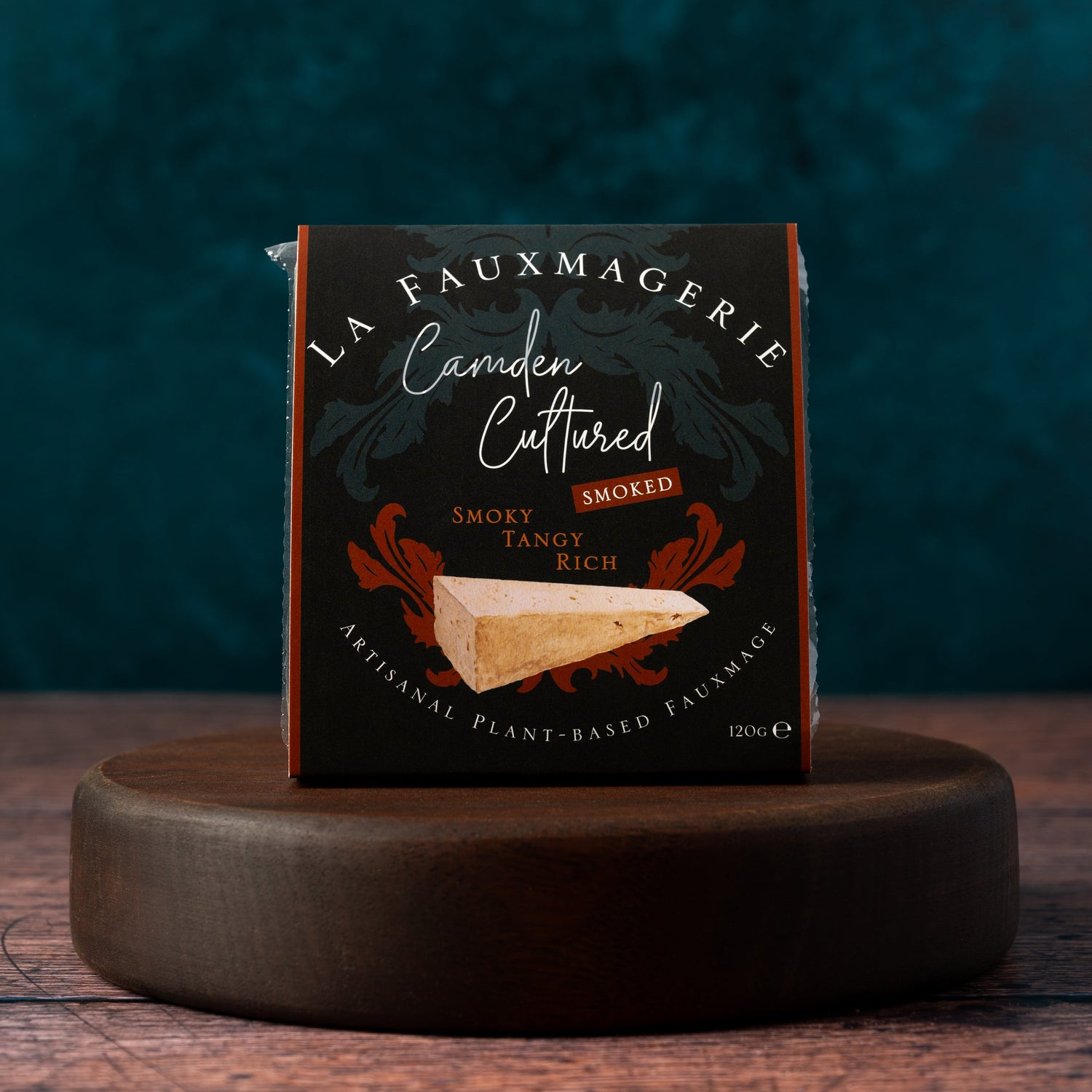 Box of 'La Fauxmagerie' Camden Cultured Smoked cheese on a wooden stand with a dark background
