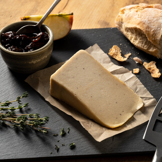 camden cultured cheese on a slate board with jam, bread, and herbs on a wooden table